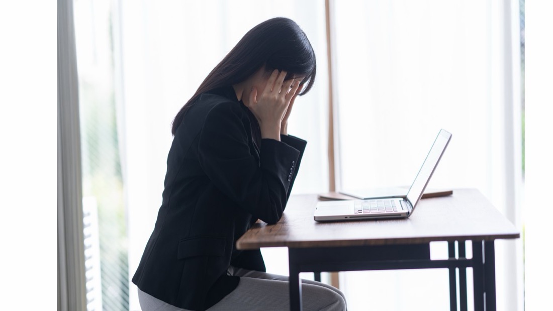 窓際のデスクで頭を抱えている様子